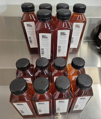 Rows of bottled GypsyRaven Homestead elderberry orange herbal tea with black caps